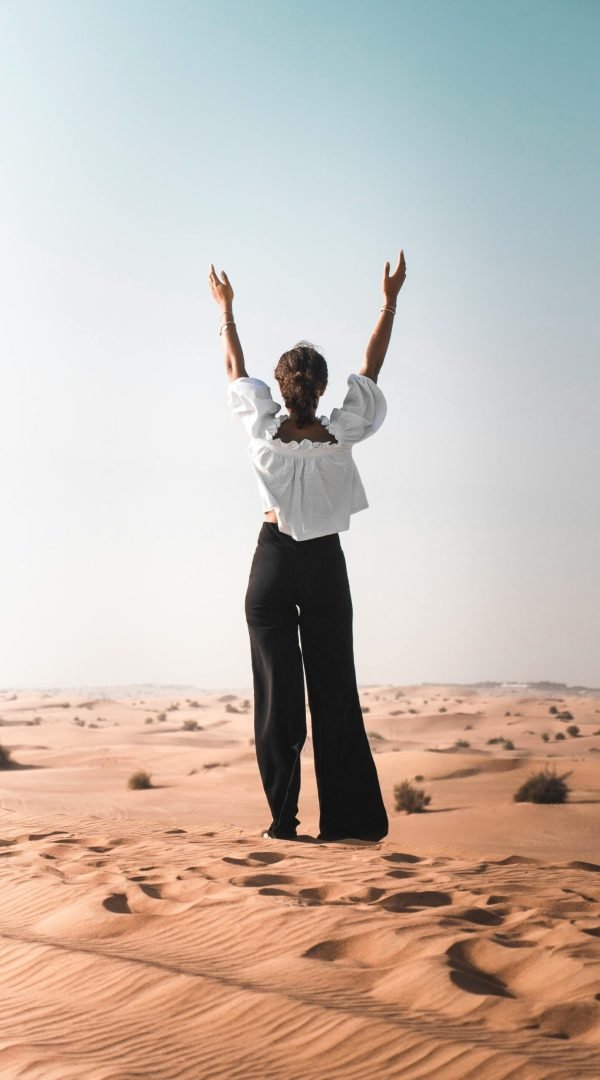 pexels-photo-2451595-2451595 A woman stands in Dubai's desert with arms raised, symbolizing freedom and solitude.