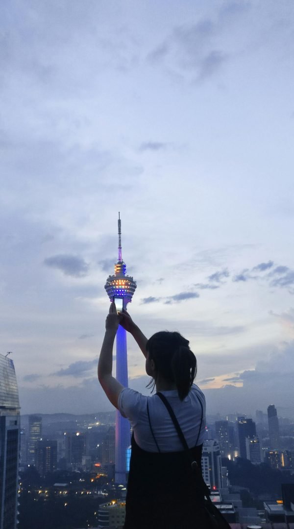 pexels-photo-928222-928222 Silhouette of a woman capturing Kuala Lumpur skyline with KL Tower at twilight.